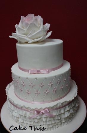 <p>こちらは豪華な３段のウェディングケーキ。 ピンク×ホワイトのガーリーなデザイン。どんなタイプのデザインでもセンスよく仕上げてくれるのは頼もしい！</p>
